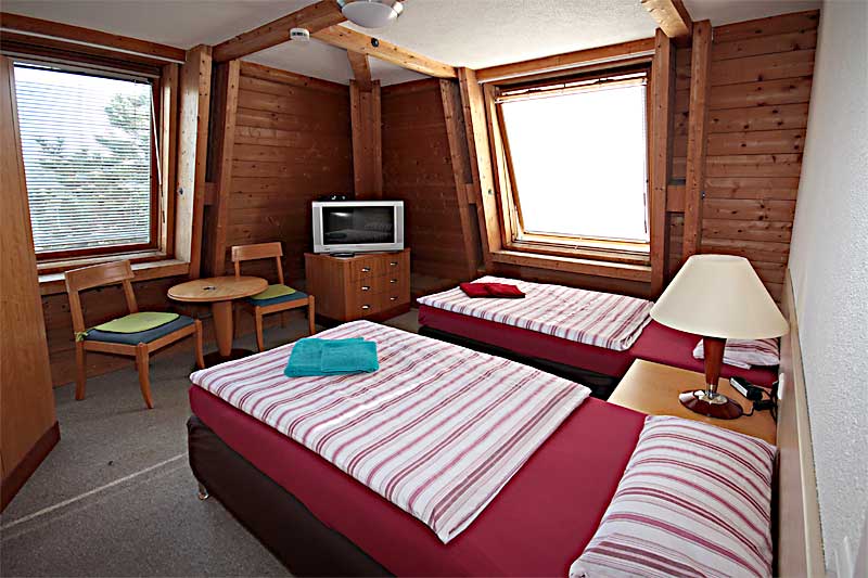 Zweibettzimmer mit Betten, TV, Schrank und Sitzgruppe Pension Bianca